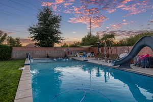 View of swimming pool with a fenced backyard, a water slide, and a patio