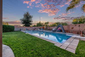 View of pool featuring a water slide, a fenced backyard, a diving board, and a patio area