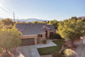 View of front of home featuring a mountain view, an attached garage, concrete driveway, stucco siding, and a front yard