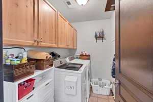 Laundry room featuring cabinet space, light tile patterned flooring, and washer and dryer