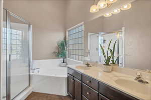 Bathroom with a garden tub, a shower stall, double vanity, and dark tile patterned floors