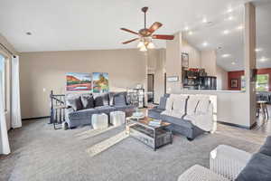 Living room with high vaulted ceiling, ceiling fan, carpet, and tile patterned floors