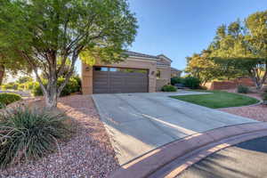View of front facade featuring driveway, stucco siding, a tile roof, and a garage