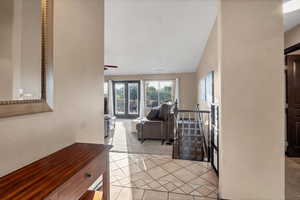 Living room featuring light colored carpet, light tile patterned floors, vaulted ceiling, and a textured wall