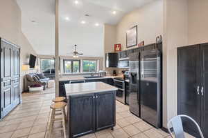 Kitchen featuring appliances with stainless steel finishes, a center island, light countertops, high vaulted ceiling, and light tile patterned floors