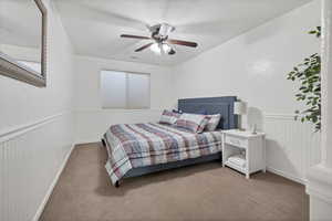 Carpeted bedroom with wainscoting and a ceiling fan