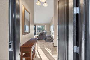 Hall with light tile patterned flooring and vaulted ceiling