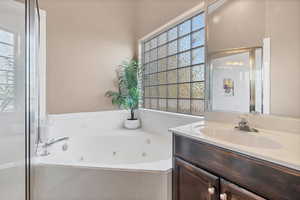 Full bathroom featuring a jetted tub, vanity, and a shower stall