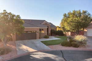 View of front facade featuring a front yard, concrete driveway, stucco siding, a garage, and a tiled roof