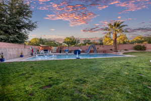 Pool at dusk featuring a fenced backyard and a patio area