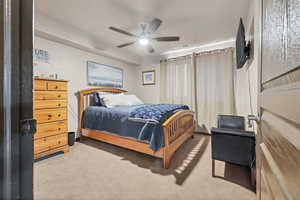 Carpeted bedroom with a ceiling fan