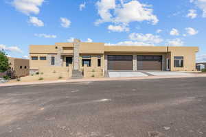 View of front of house featuring stone siding, stucco siding, concrete driveway, and an attached garage
