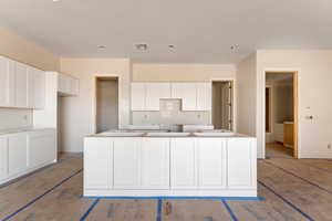 Kitchen featuring visible vents, white cabinets, and a center island