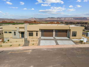 View of front facade featuring stucco siding, a mountain view, concrete driveway, and a garage