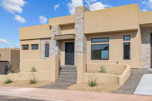 View of front of house with stucco siding and stone siding