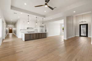 Kitchen featuring open floor plan, white cabinetry, a large island, decorative backsplash, and ceiling fan