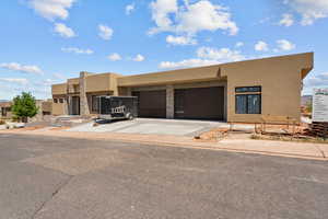 Pueblo-style house featuring a garage, stucco siding, and concrete driveway