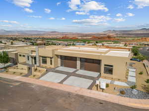 View of front of home with stucco siding, a mountain view, concrete driveway, and an attached garage
