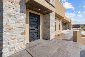 Property entrance with stone siding and stucco siding