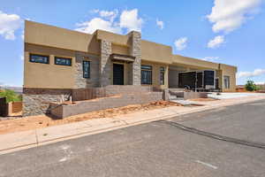 View of front facade featuring stucco siding and stone siding