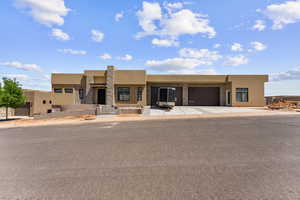 Southwest-style home featuring stucco siding, driveway, an attached garage, and stone siding