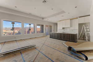 Kitchen with a raised ceiling, visible vents, white cabinets, and a center island