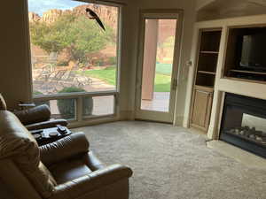 Primary Suite Den with Carpeted living area featuring a multi sided fireplace and built in shelves