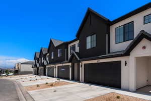View of front of house featuring stucco siding, a residential view, a garage, and concrete driveway