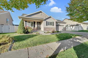 View of front facade featuring stone siding, a porch, driveway, a gate, and a garage