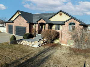 View of front of home featuring concrete driveway, brick siding, an attached garage, and roof with shingles