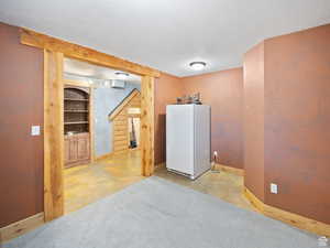 Finished below grade area with freestanding refrigerator, a textured ceiling, and baseboards