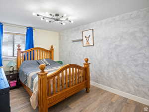 Bedroom with baseboards, wood finished floors, and a notable chandelier