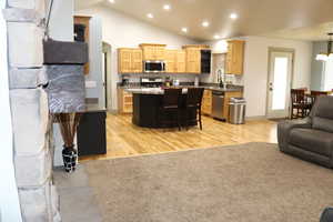 Living area featuring recessed lighting, vaulted ceiling, light wood-style flooring, and arched walkways