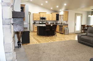 Kitchen with light wood finish cabinetry, open floor plan, a center island, stainless steel appliances, and a kitchen breakfast bar