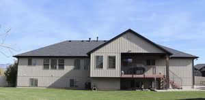 Back of property featuring a lawn, a shingled roof, a patio area, and a balcony