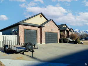 View of front facade with a garage, fence, brick siding, a mountain view, and driveway