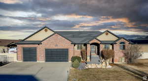 Ranch-style home with brick siding, a garage, roof with shingles, and concrete driveway