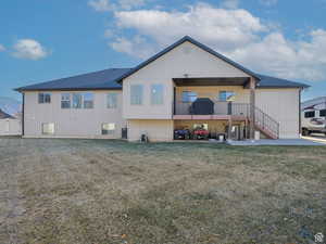 Back of house with a shingled roof, a yard, and stairway