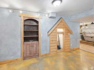 Unfurnished living room featuring a textured ceiling, rail lighting, and finished concrete floors