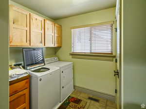Washroom featuring visible vents, washer and dryer, baseboards, cabinet space, and light tile patterned floors