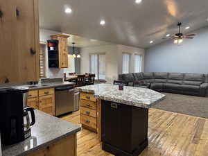 Kitchen featuring light wood-style floors, a center island, recessed lighting, dishwasher, and lofted ceiling