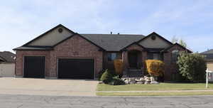 View of front of house featuring a garage, concrete driveway, brick siding, and a front yard