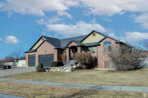 Single story home with an attached garage, a front yard, brick siding, and concrete driveway