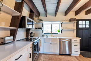 Kitchen featuring open shelves, white cabinetry, stainless steel appliances, plenty of natural light, and beam ceiling
