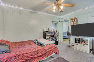 Carpeted bedroom with a ceiling fan