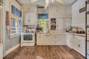 Kitchen with white cabinetry, white range with electric cooktop, light countertops, dark wood-type flooring, and a ceiling fan