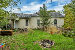 Back of property featuring an outdoor fire pit, brick siding, and a lawn
