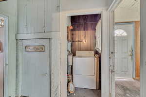 Laundry room with dryer and wood walls