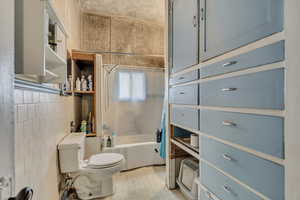 Bathroom featuring shower / bathtub combination with curtain and tile walls