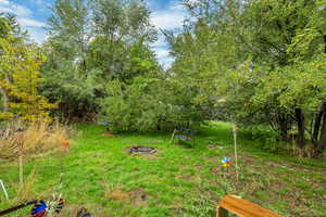 View of back yard featuring a fire pit and mature trees